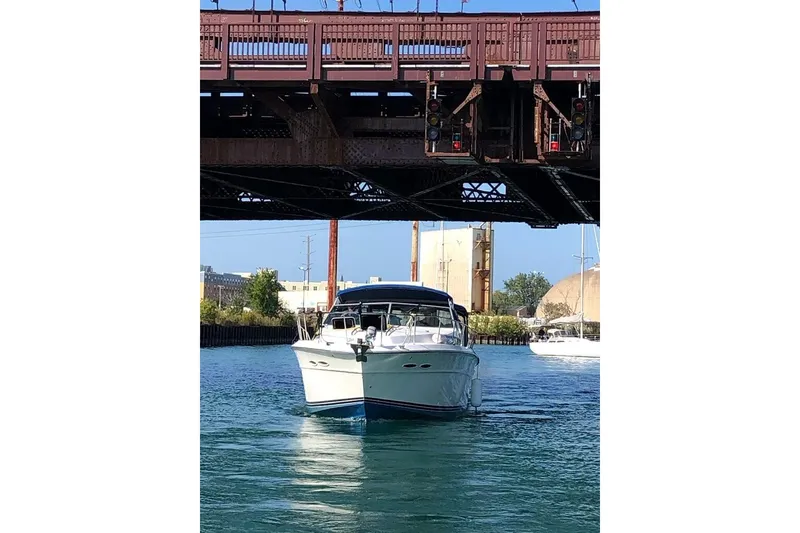 Slide: The Image of 1988 Sea Ray 390 Express Cruiser navigating under a bridge on a sunny day. - 32