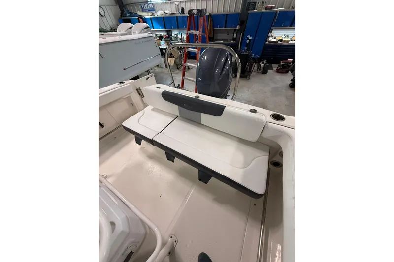 Slide: The Image of 2021 Robalo R222 Center Console boat interior with seating and engine in a workshop. - 13