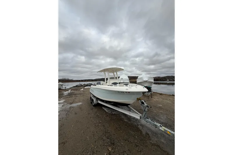 Slide: The Image of 2021 Robalo R222 Center Console boat on trailer by a lake under cloudy skies. - 3