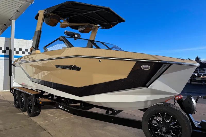 Slide: The Image of 2026 Nautique Super Air Nautique G25 boat on trailer, beige and black design, sunny day. - 9