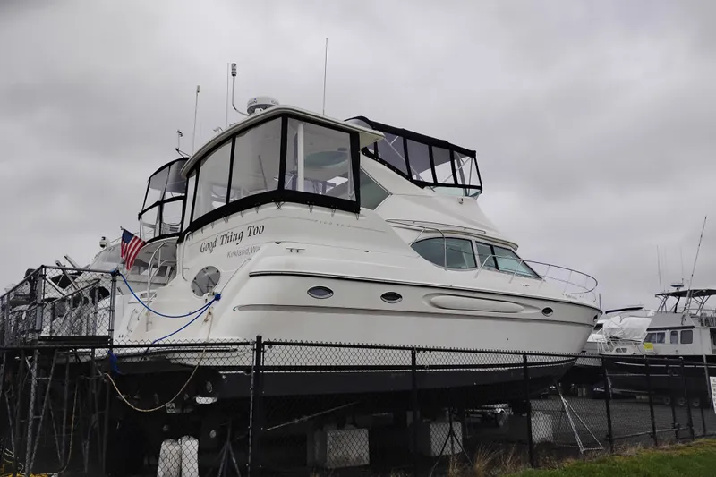 Slide: The Image of 2001 Maxum 4100 SCA yacht on dry dock, overcast sky, American flag displayed. - 1