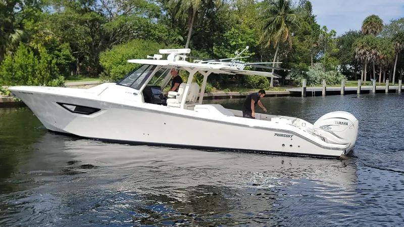 Slide: The Image of 2021 Pursuit S 378 Sport boat cruising on a calm river with lush greenery. - 12