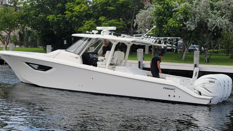 Slide: The Image of 2021 Pursuit S 378 Sport boat on a calm river near a green park. - 16