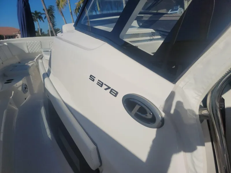 Slide: The Image of 2021 Pursuit S 378 Sport boat, sleek white exterior, sunny day, palm trees in background. - 20