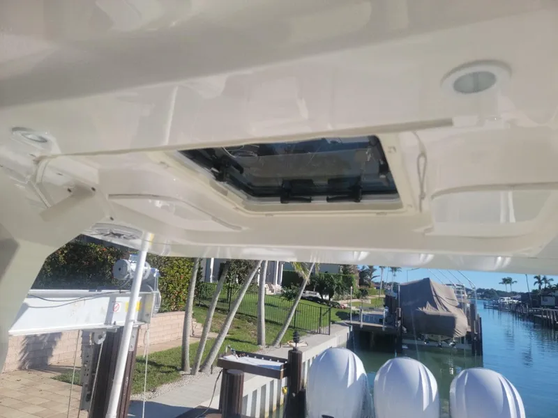 Slide: The Image of 2021 Pursuit S 378 Sport boat roof hatch, docked by waterfront homes. - 21