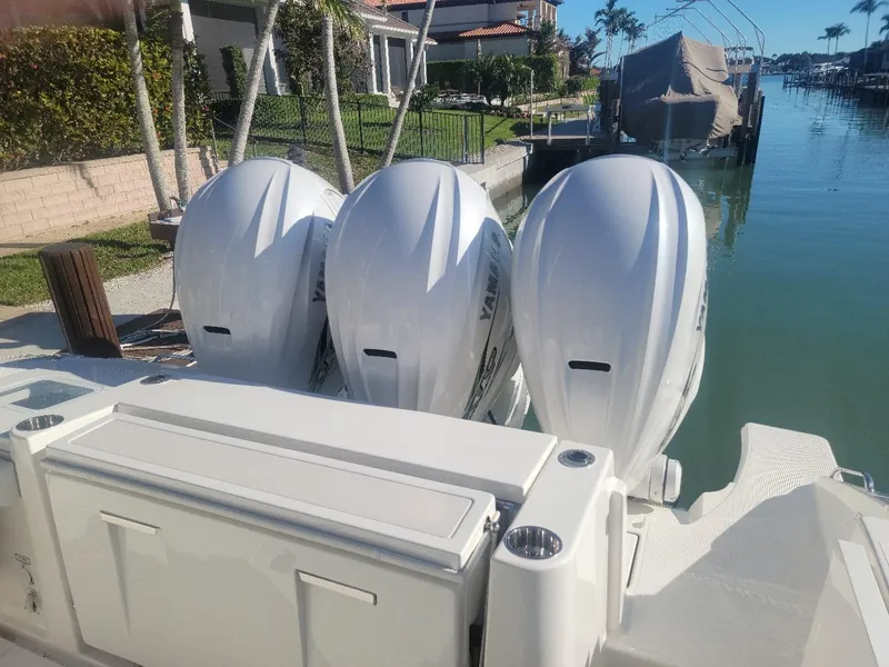 Slide: The Image of 2021 Pursuit S 378 Sport boat with triple outboard engines docked by waterfront homes. - 33
