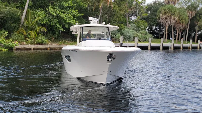 Slide: The Image of 2021 Pursuit S 378 Sport boat cruising on a calm river near lush greenery. - 5