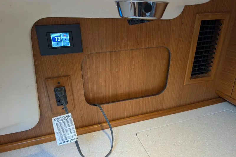 Slide: The Image of 2021 Catalina 315 interior with digital thermostat and power outlet on wooden panel. - 11