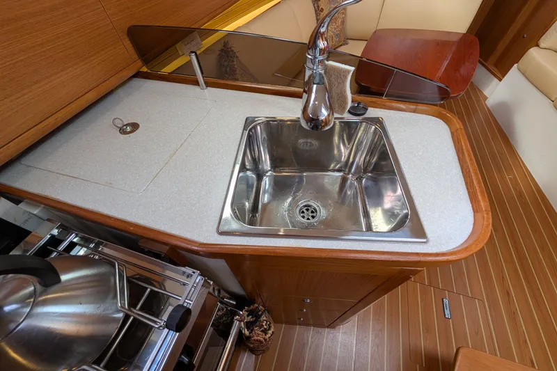 Slide: The Image of 2021 Catalina 315 yacht kitchen with stainless steel sink and wooden cabinetry. - 13