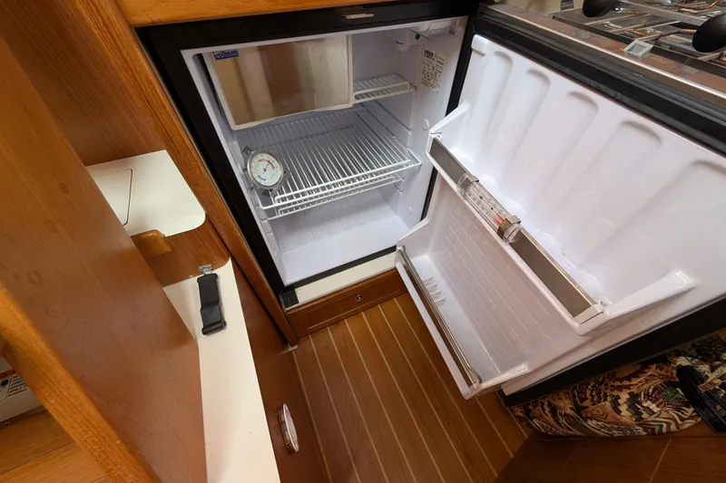 Slide: The Image of Open refrigerator inside 2021 Catalina 315 yacht, featuring wooden flooring and compact design. - 15