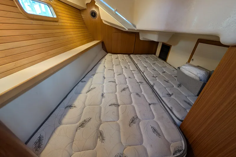 Slide: The Image of 2021 Catalina 315 yacht interior cabin with twin mattresses and wooden paneling. - 23