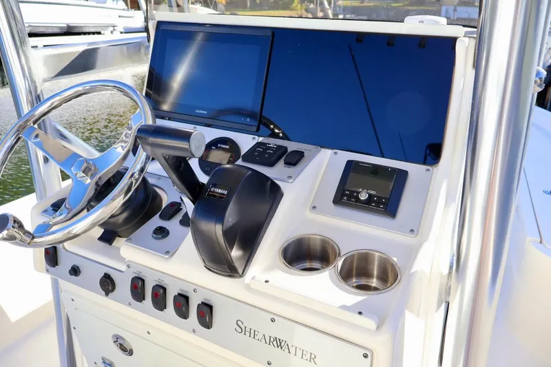 Slide: The Image of 2022 ShearWater 23LTZ boat dashboard with steering wheel, controls, and display screens. - 10