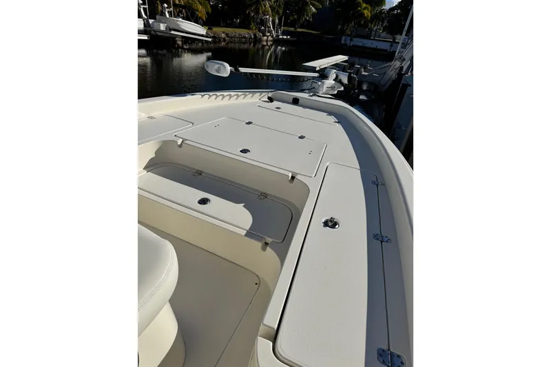 Slide: The Image of 2022 ShearWater 23LTZ boat deck with storage compartments, docked by a serene waterfront. - 18