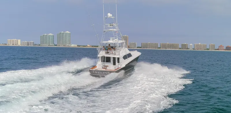 Slide: The Image of 2003 Hatteras 60 Convertible yacht cruising near coastal city. - 39