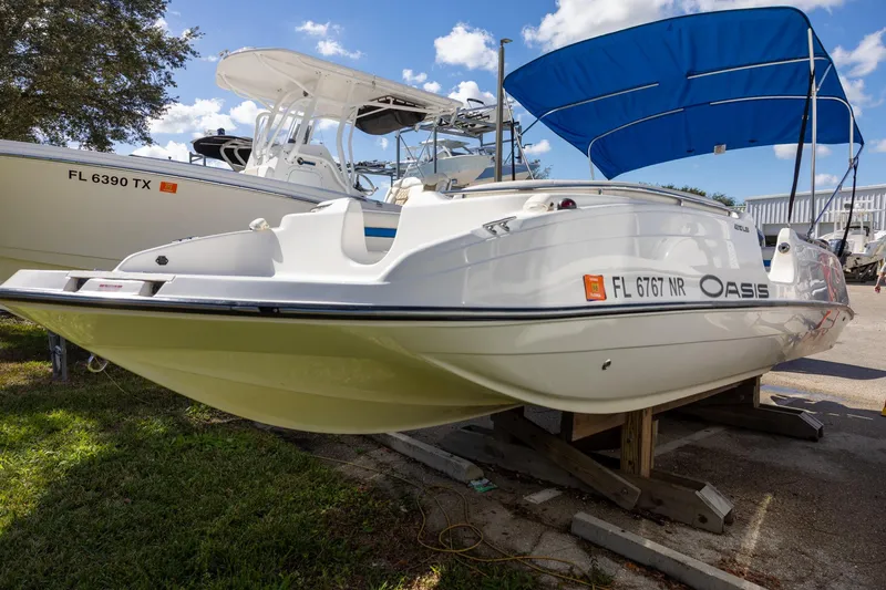 Slide: The Image of 2008 Key West 210 LS boat with blue canopy, parked on a trailer under a clear sky. - 0