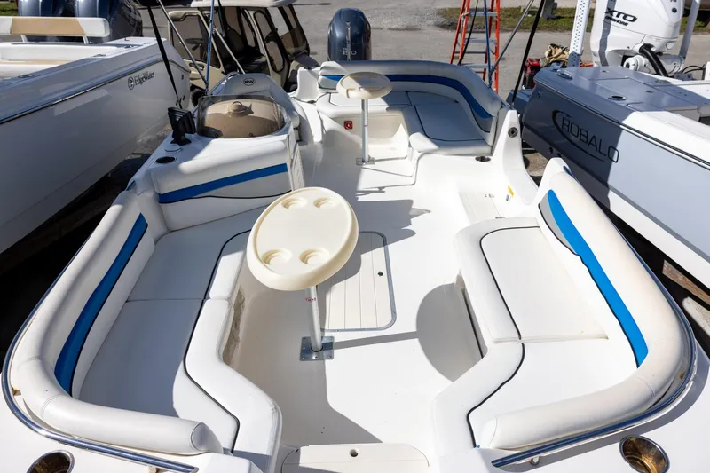Slide: The Image of 2008 Key West 210 LS boat interior with white and blue seating, cup holders, and spacious layout. - 12