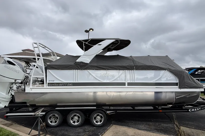 The Image of 2026 JC Sporttoon 26TT pontoon boat on trailer, covered, with dual outboard engines. - 0