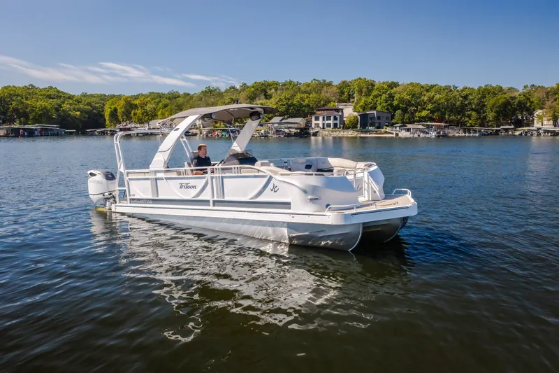 The Image of 2026 JC Sporttoon 26TT pontoon boat cruising on a scenic lake. - 0