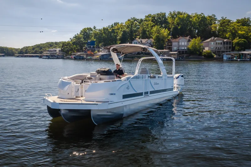Slide: The Image of 2026 JC Sporttoon 26TT pontoon boat on a scenic lake with lush shoreline. - 58