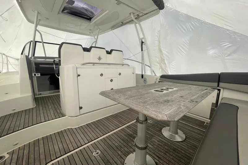 Slide: The Image of 2019 Jeanneau Leader 10.5 boat interior with seating and wooden table. - 3