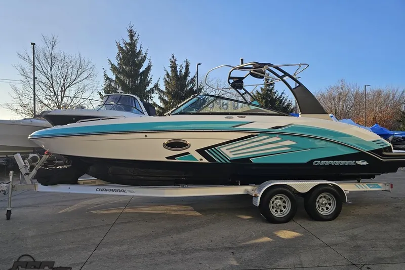 Slide: The Image of 2016 Chaparral Vortex 243 VRX boat on trailer, teal and white design, parked outdoors. - 17