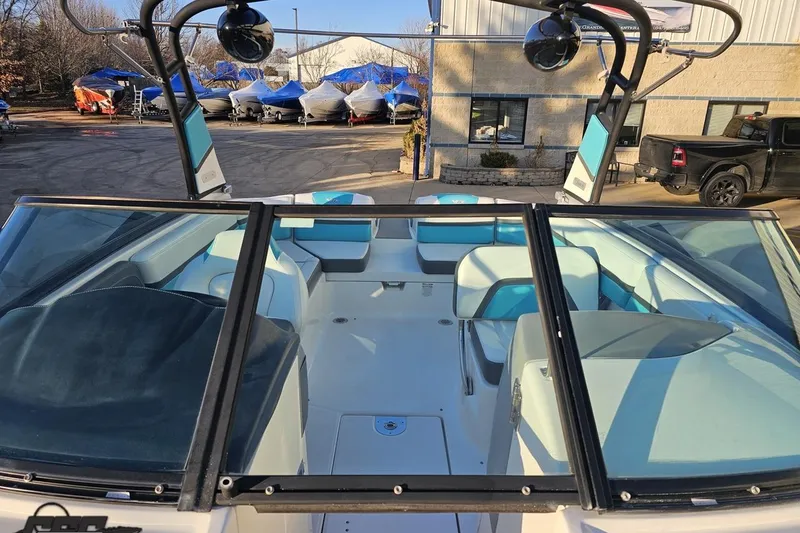 Slide: The Image of 2016 Chaparral Vortex 243 VRX boat interior with blue and white seating, parked outdoors. - 80
