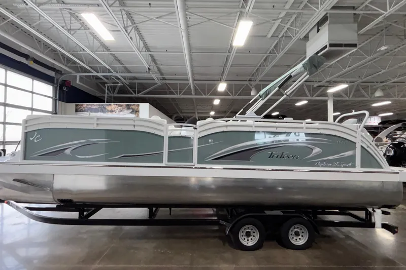 The Image of 2026 JC Neptoon 25TT Sport pontoon boat displayed indoors on a trailer. - 1