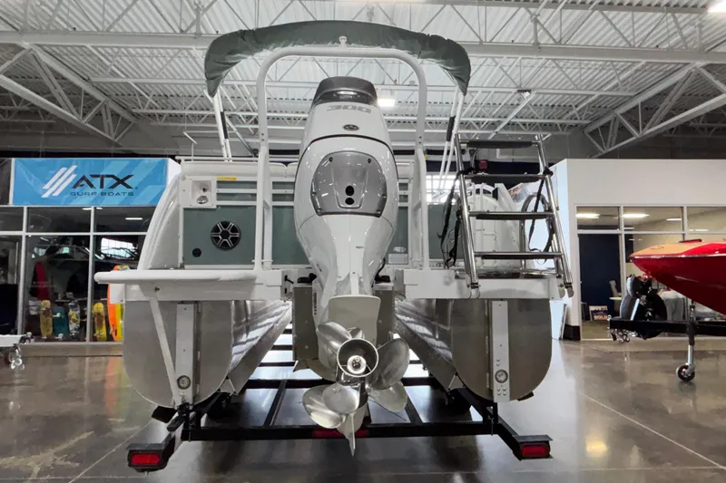 Slide: The Image of 2026 JC Neptoon 25TT Sport pontoon boat in showroom, rear view with motor and ladder. - 4