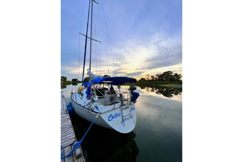 The Image of 1984 C&C 35-3 sailboat docked at sunset, reflecting on calm water. - 1