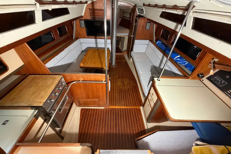 Slide: The Image of 1984 C&C 35-3 yacht interior with wood finish, seating, and kitchen area. - 11