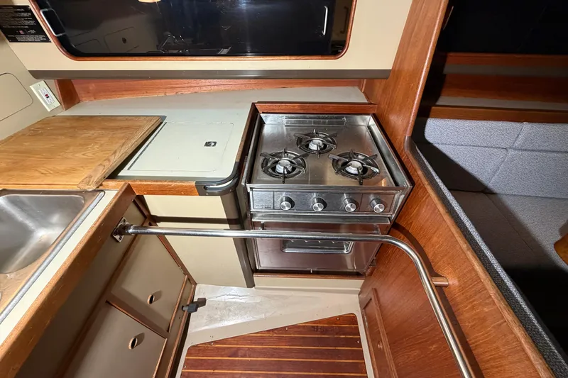 Slide: The Image of 1984 C&C 35-3 yacht kitchen with stove, sink, and wooden cabinetry. - 19