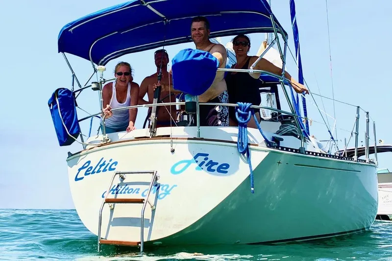 Slide: The Image of 1984 C&C 35-3 sailboat "Celtic Fire" with people onboard, sailing in clear waters. - 2