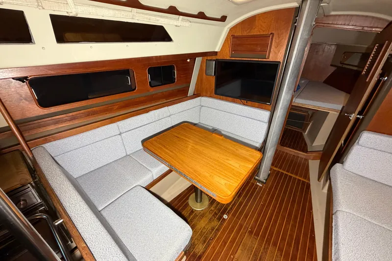 Slide: The Image of 1984 C&C 35-3 yacht interior with wood accents, cozy seating, and a mounted TV. - 27