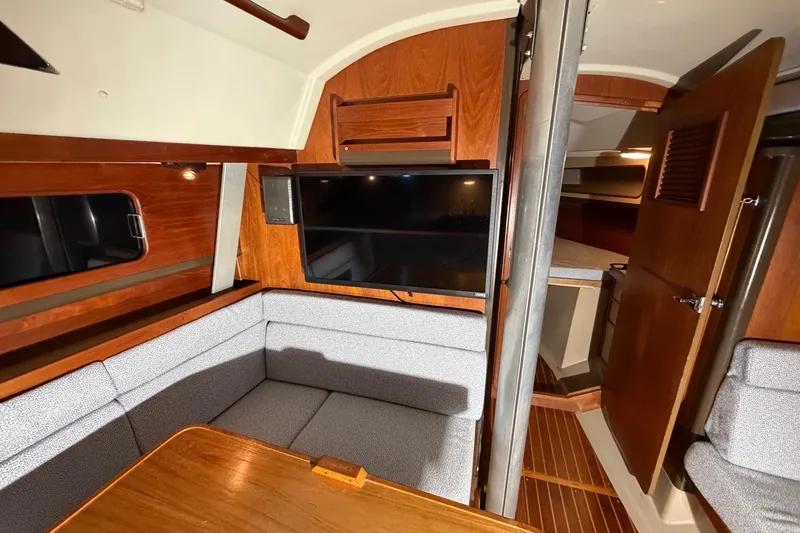Slide: The Image of 1984 C&C 35-3 yacht interior with cozy seating, wood accents, and mounted TV. - 28