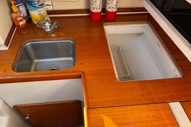 Slide: The Image of 1994 Catalina 270 boat kitchen with sink, wooden countertop, and fire extinguishers. - 15