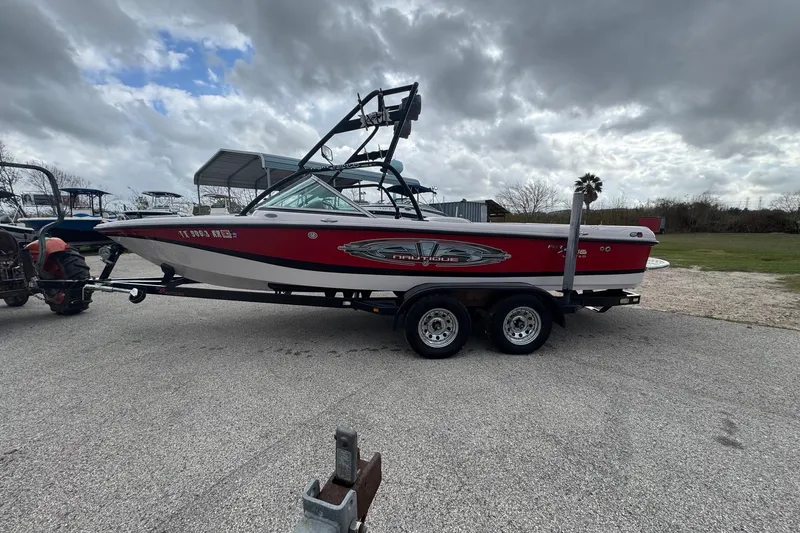 Slide: The Image of 2004 Correct Craft Air Nautique 216 Limited boat on trailer under cloudy sky. - 3
