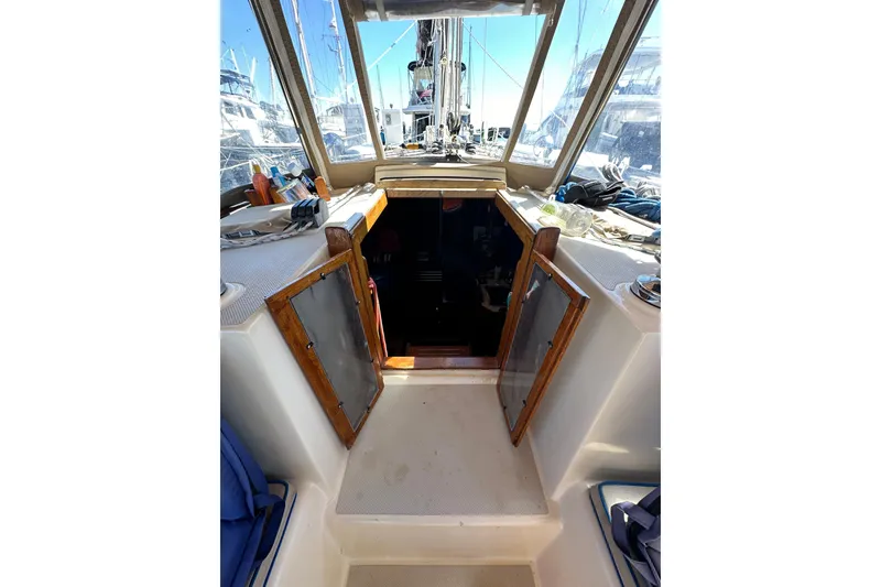 Slide: The Image of 1991 Island Packet 35 sailboat cockpit with open cabin doors, showcasing interior access. - 16