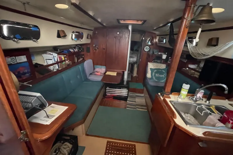 Slide: The Image of Interior of a 1991 Island Packet 35 sailboat, featuring cozy seating and a compact kitchen area. - 17