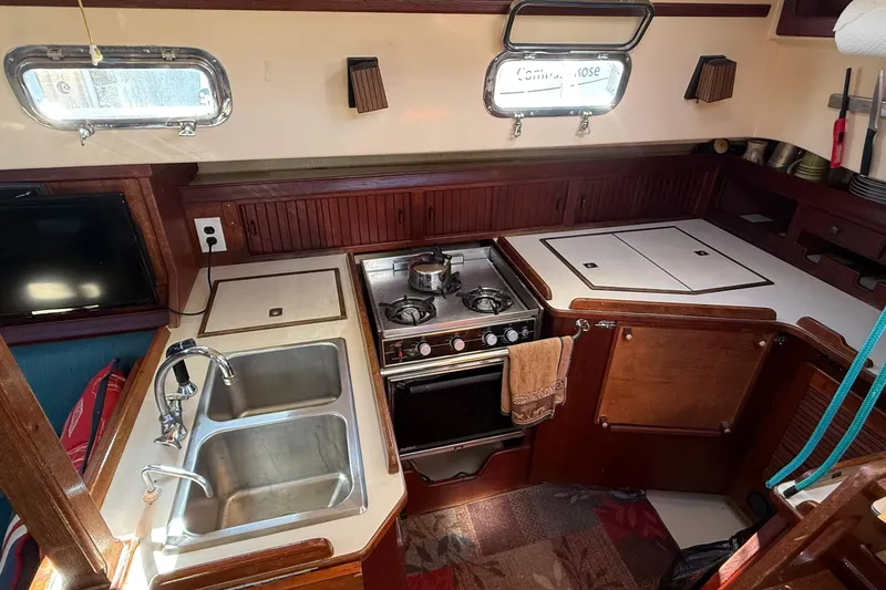 Slide: The Image of 1991 Island Packet 35 yacht kitchen with stove, sink, and wooden cabinetry. - 18