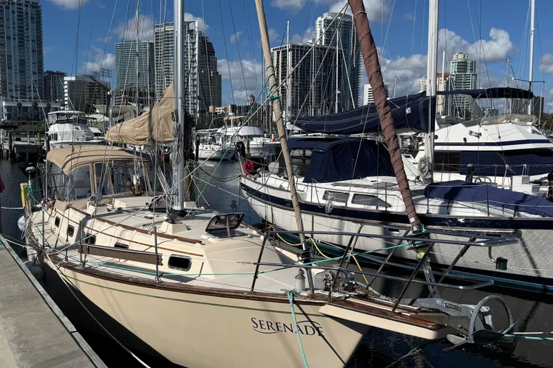 Slide: The Image of 1991 Island Packet 35 sailboat docked in marina with city skyline background. - 2