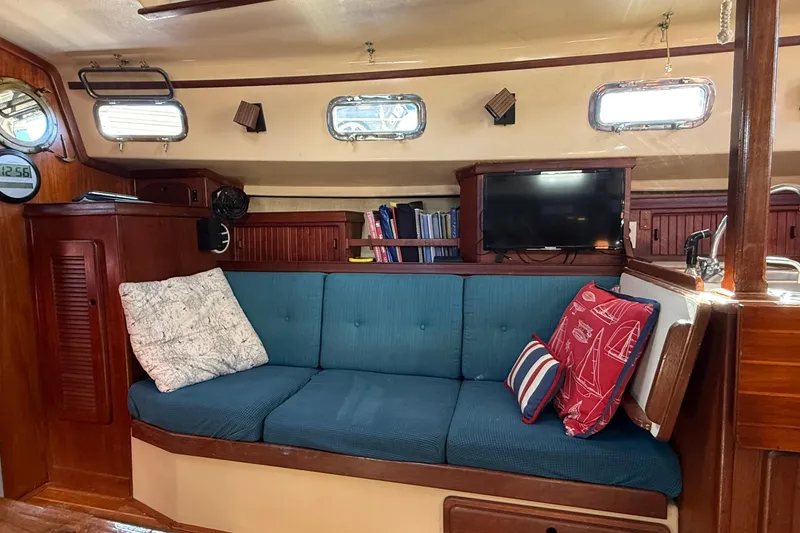 Slide: The Image of Interior of 1991 Island Packet 35 sailboat with blue cushioned seating and nautical decor. - 24