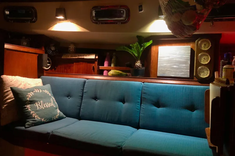 Slide: The Image of Cozy interior of 1991 Island Packet 35 sailboat with blue seating and decorative pillows. - 25