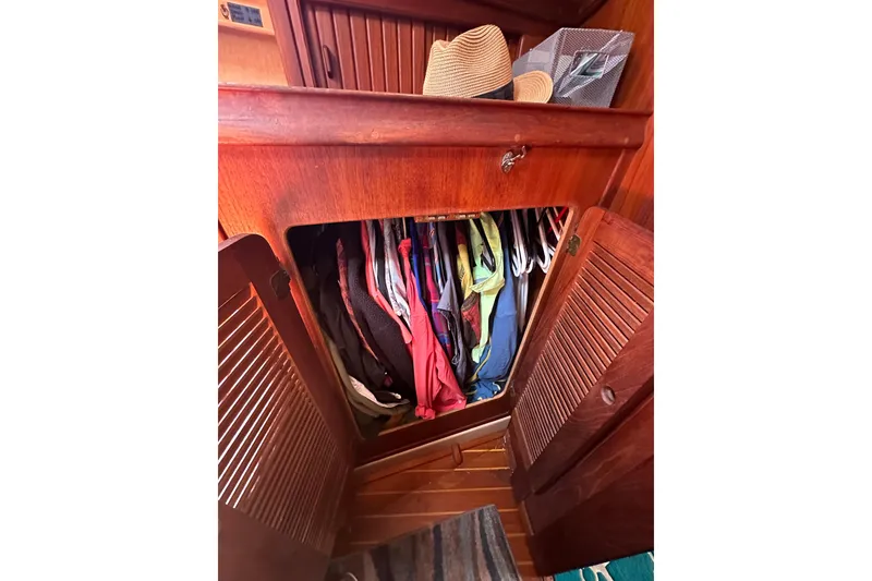 Slide: The Image of Wooden closet with clothes and hats inside a 1991 Island Packet 35 sailboat. - 28