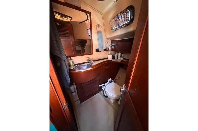 Slide: The Image of 1991 Island Packet 35 yacht bathroom with sink, toilet, and wooden cabinetry. - 31