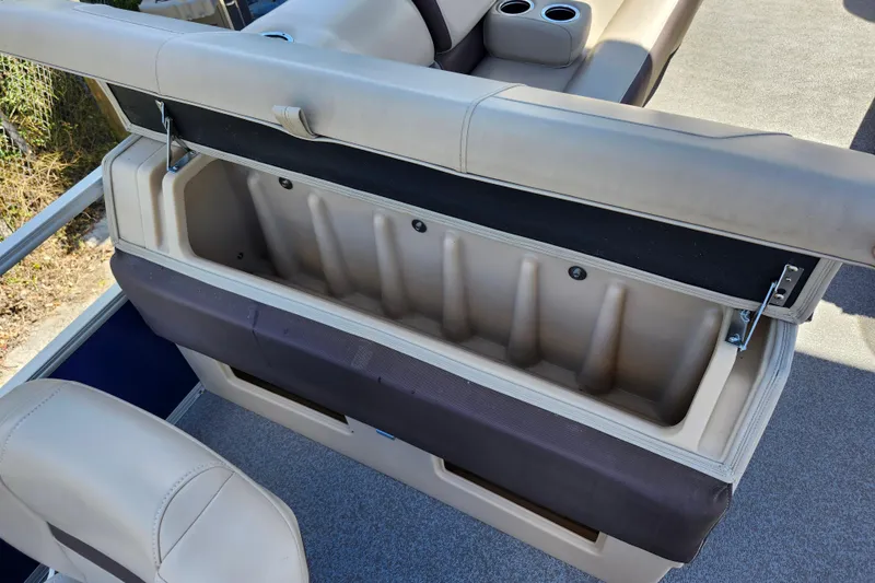 Slide: The Image of 2018 Sun Tracker Fishin' Barge 22 DLX storage compartment with beige seating and cup holders. - 20