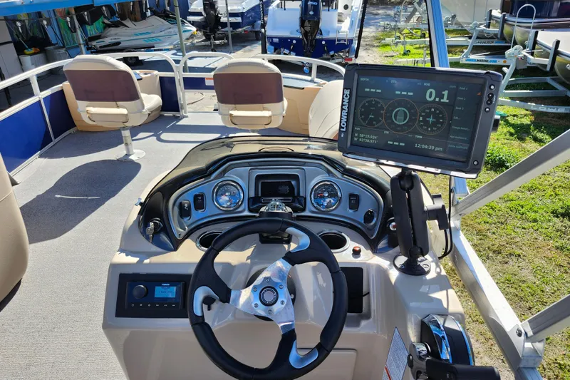 Slide: The Image of 2018 Sun Tracker Fishin' Barge 22 DLX dashboard with steering wheel and navigation display. - 22