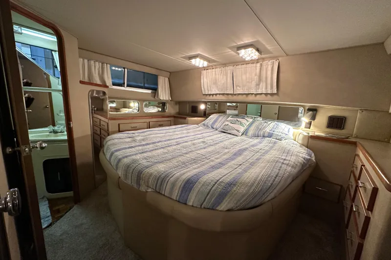Slide: The Image of Interior of 1986 Chris-Craft 381 Catalina yacht, featuring a cozy bedroom with striped bedding. - 16