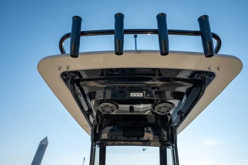 Slide: The Image of 2026 Scout 220 XSF boat's T-top with rod holders and speakers against blue sky. - 11