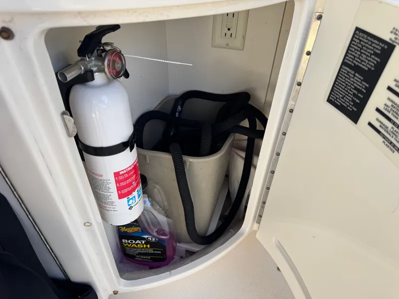 Slide: The Image of Fire extinguisher and cleaning supplies in a 2002 Sea Ray 290 Bowrider storage. - 36