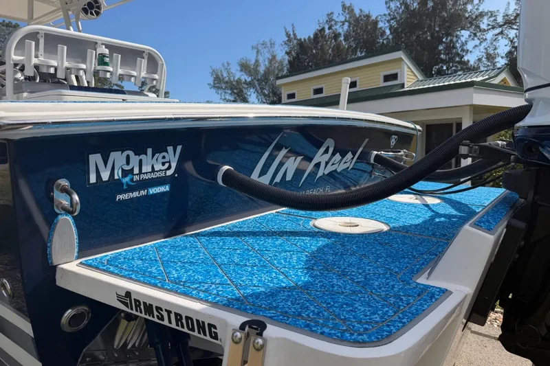 Slide: The Image of 2004 Jupiter 31 Cuddy boat with blue deck, docked near a house, featuring brand logos. - 15